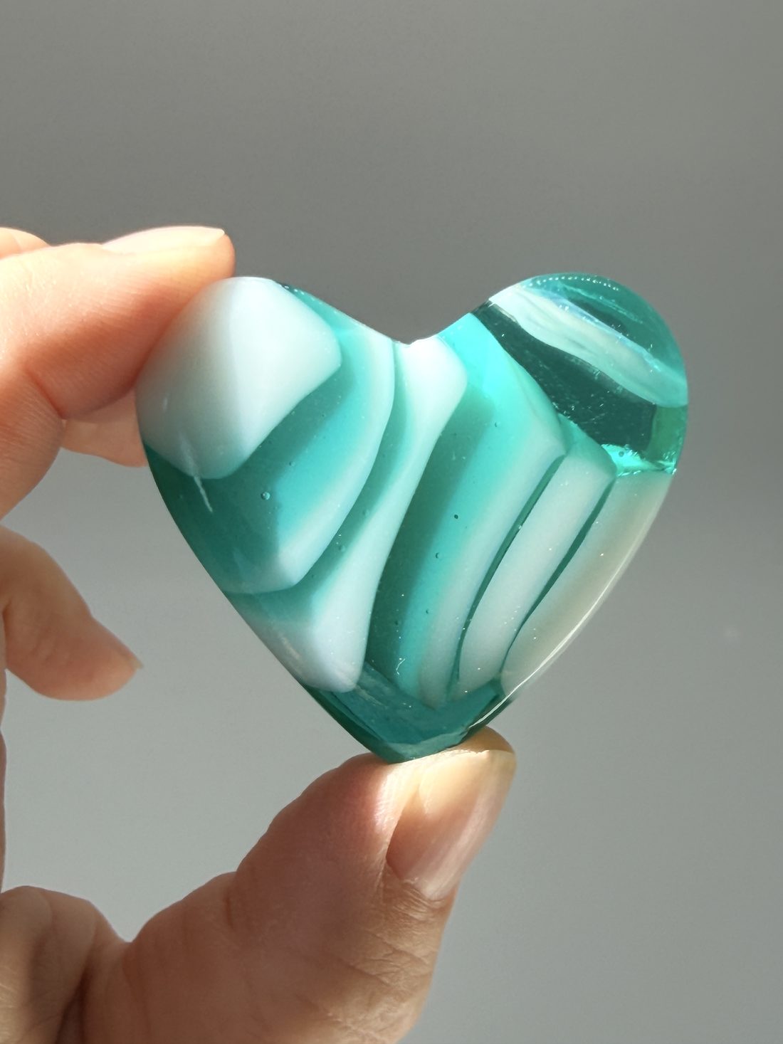 A teal and white fused glass candy heart