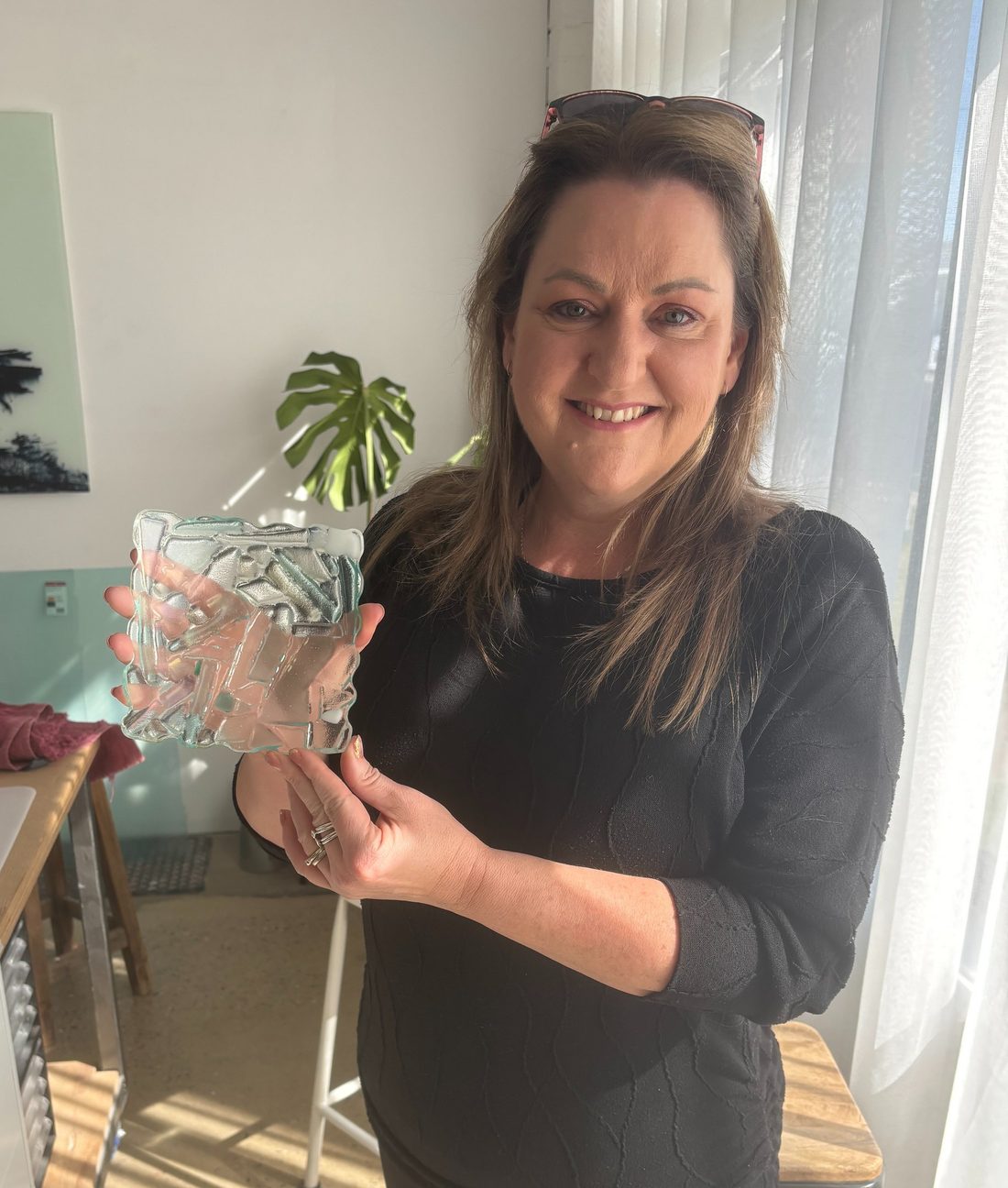 Lisa holding a finished fused glass bowl